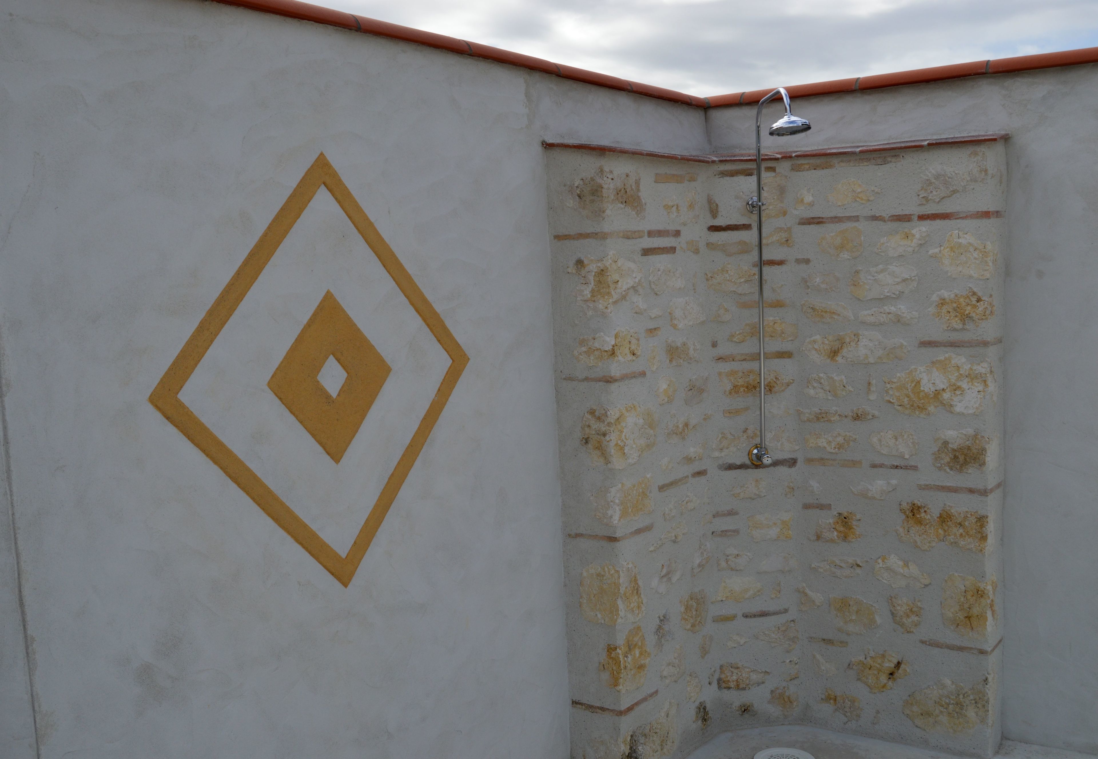 A bathroom with a shower, a wall with a diamond-shaped design, and a tiled wall.