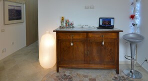 A wooden cabinet with a laptop, a vase with flowers, and a tall vase with a light. - Il Nespolo Sassi Affittacamere (Matera)
