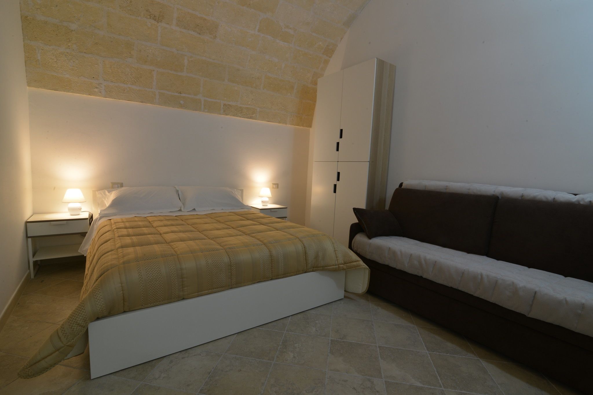 Une chambre à coucher comprenant un lit, des tables de chevet, une commode, un canapé et une armoire.