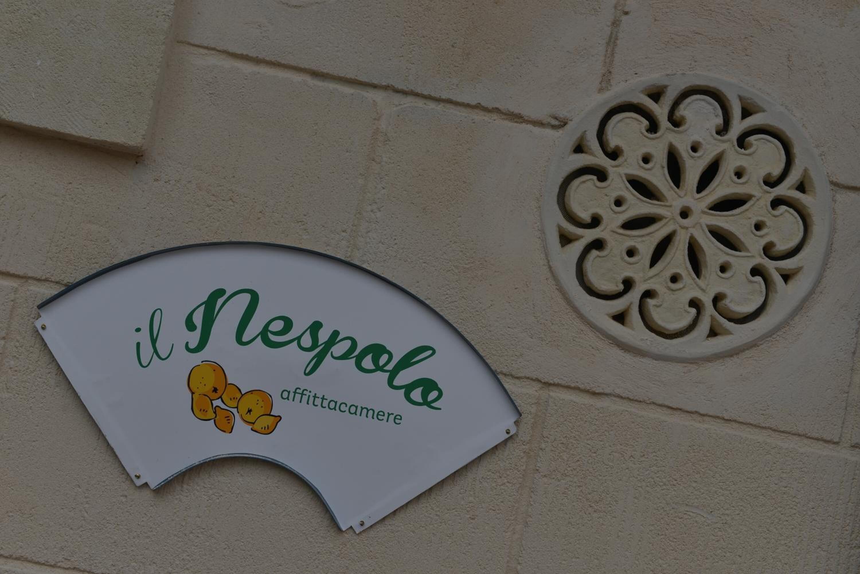 A sign with the text "il Nespolo affittacamere" on a curved white background.