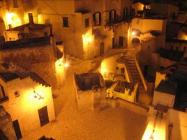 An old town square with buildings, a staircase, and street lamps.
