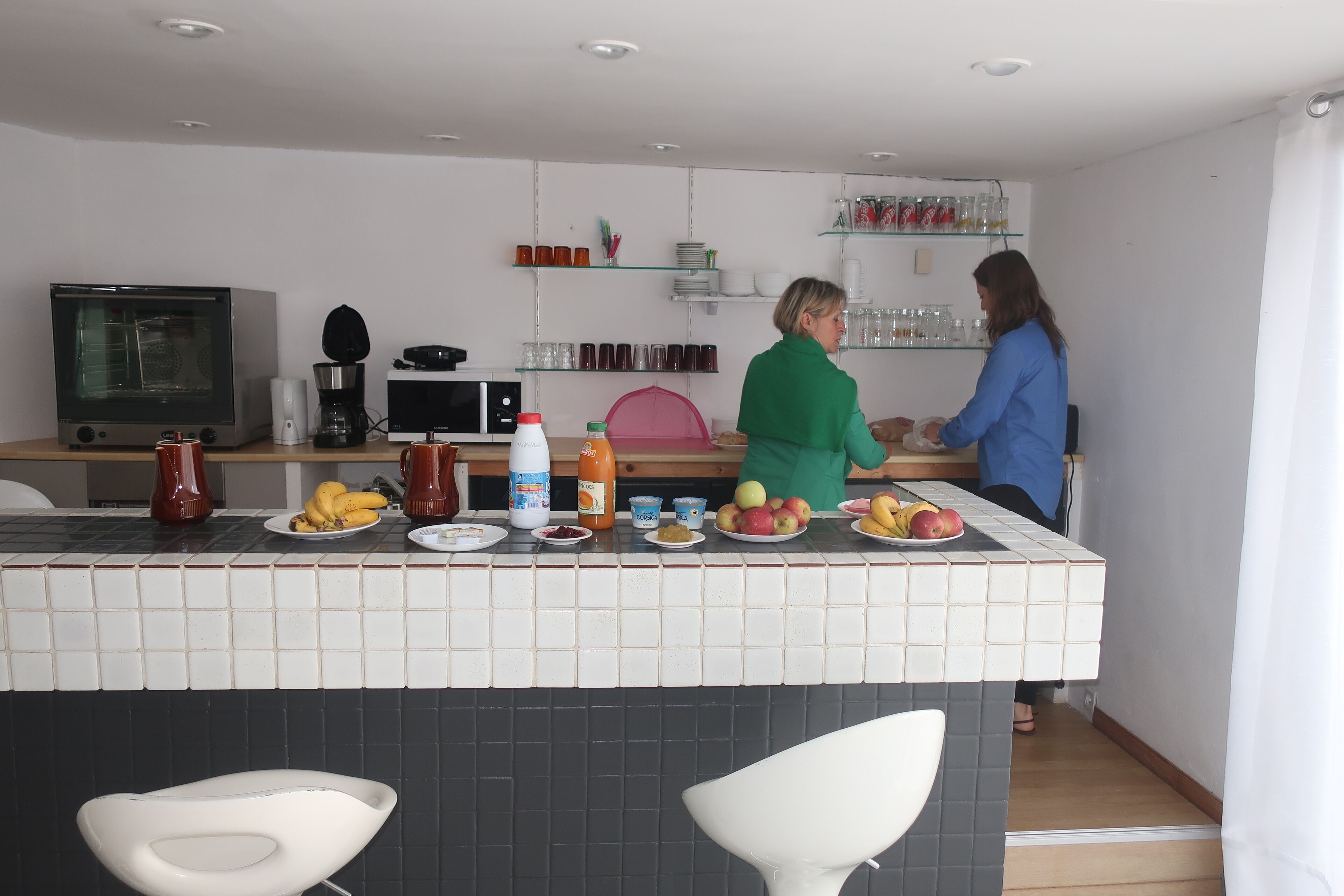 A modern kitchen with a tiled backsplash, a microwave, a coffee maker, and various kitchen utensils.
