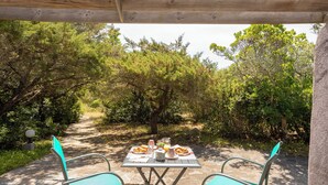 An outdoor patio with a table set for breakfast, surrounded by greenery and trees. - Domaine Bocca Di Feno (Bonifacio)