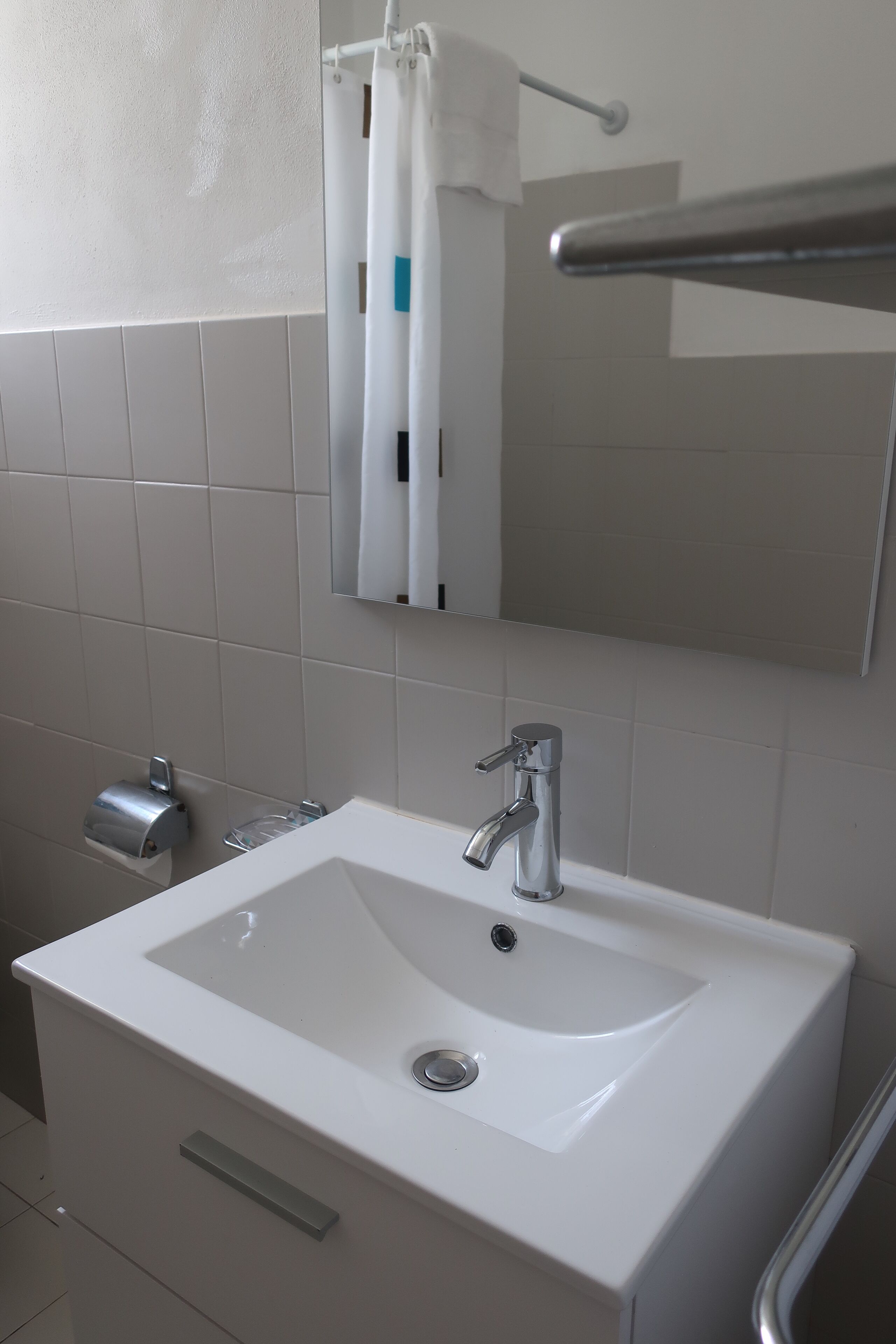 A bathroom with a white sink, a mirror, and a towel rack.