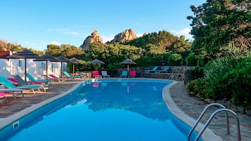 Una piscina al aire libre, sombrillas, sillones reclinables de piscina