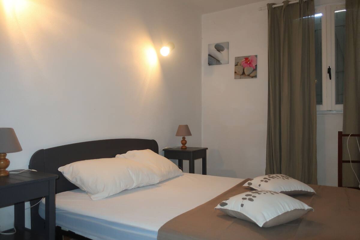 A hotel room with a bed, two bedside tables, a lamp, and a window with curtains.