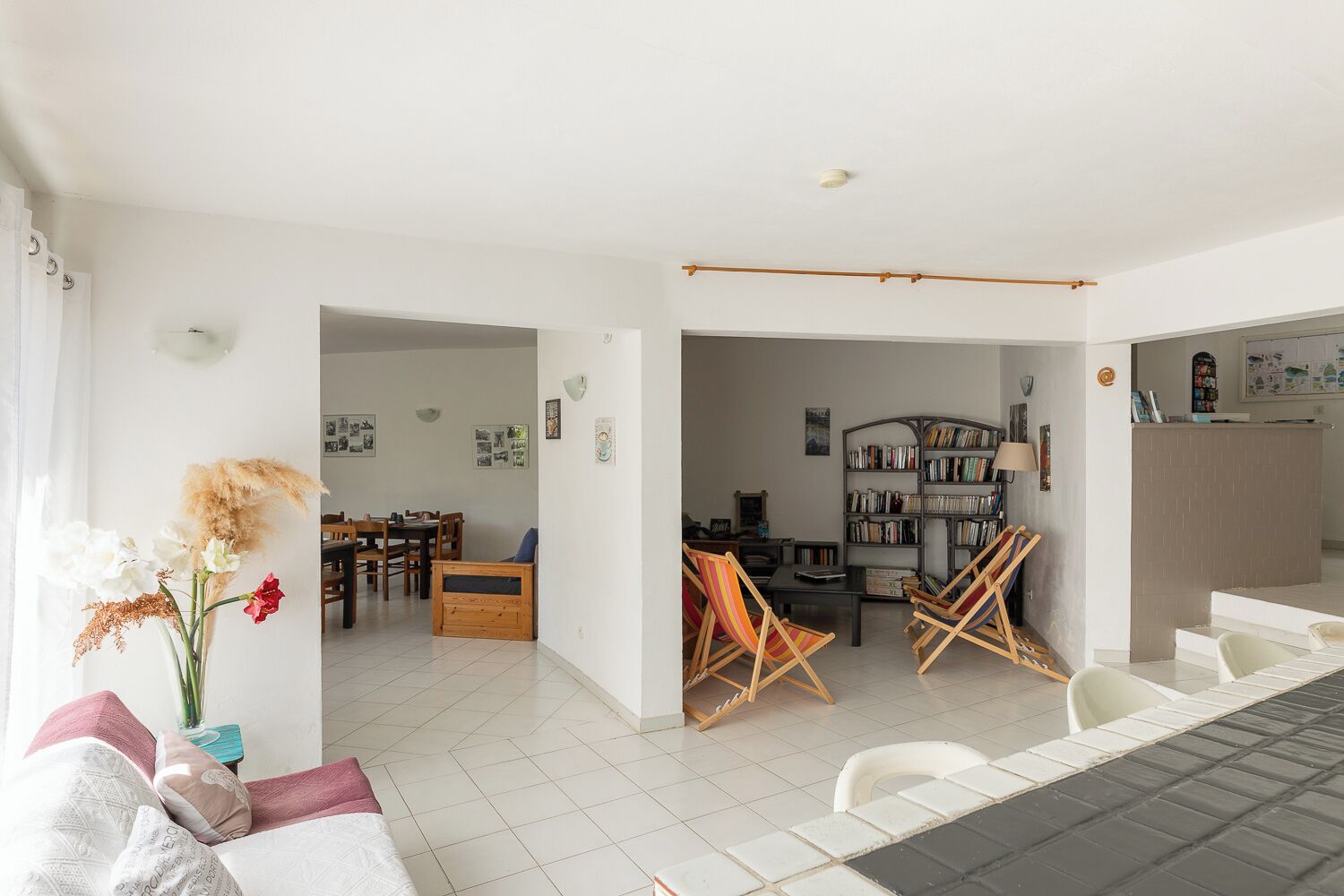 Amplia sala de estar con una mesa de comedor, sillas, un sofá y una estantería.