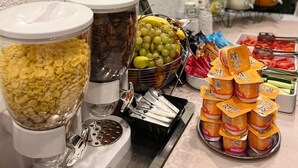 A buffet setup with various food items including fruits, cereals, and dairy products. - Elizeu Hotel (Bucharest)