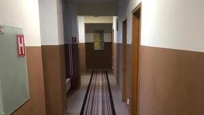 A hotel hallway with striped carpet, doors on both sides, and a fire alarm on the left. - Elizeu Hotel (Bucharest)