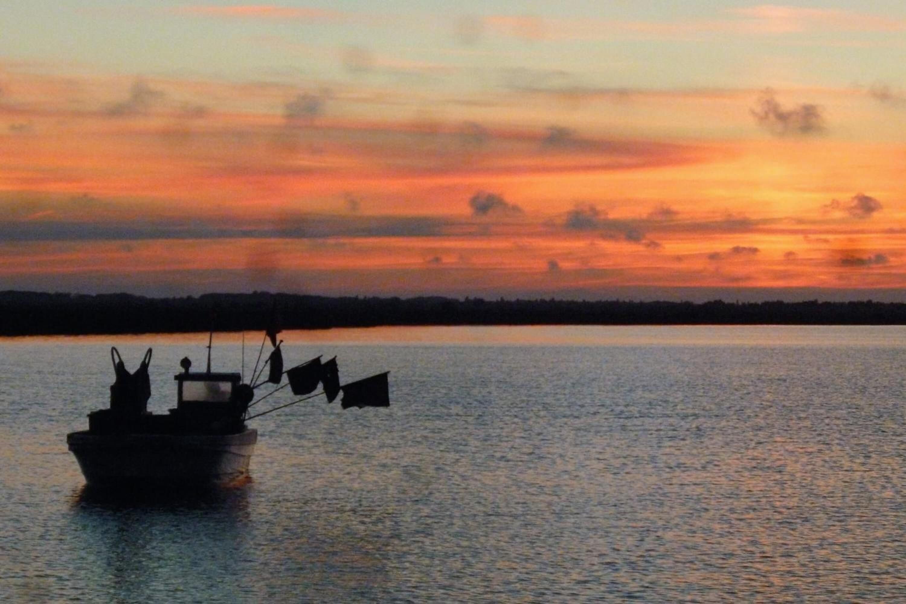 A boat on calm water during sunset.