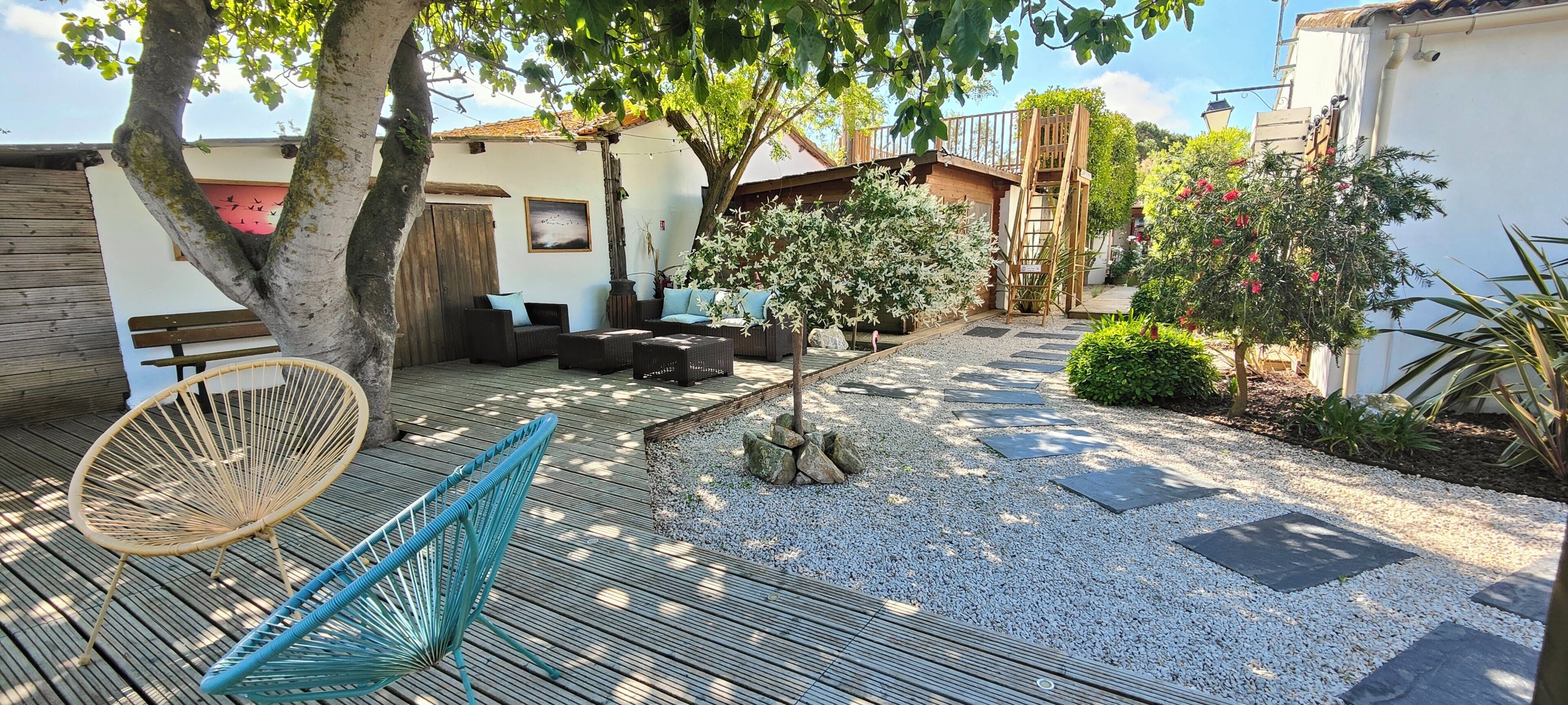 Eine Holzterrasse mit Gartenmöbeln, einer Hängematte und einem Garten mit einem Pfad.