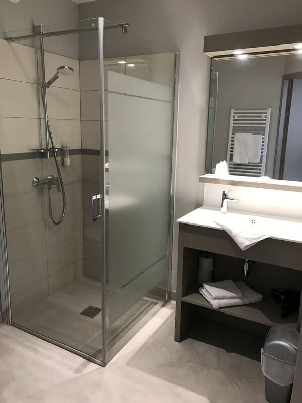 A modern bathroom with a glass-enclosed shower, a vanity with a mirror, and a towel rack. - Hôtel Les Galets Bleus (Cayeux-sur-Mer)