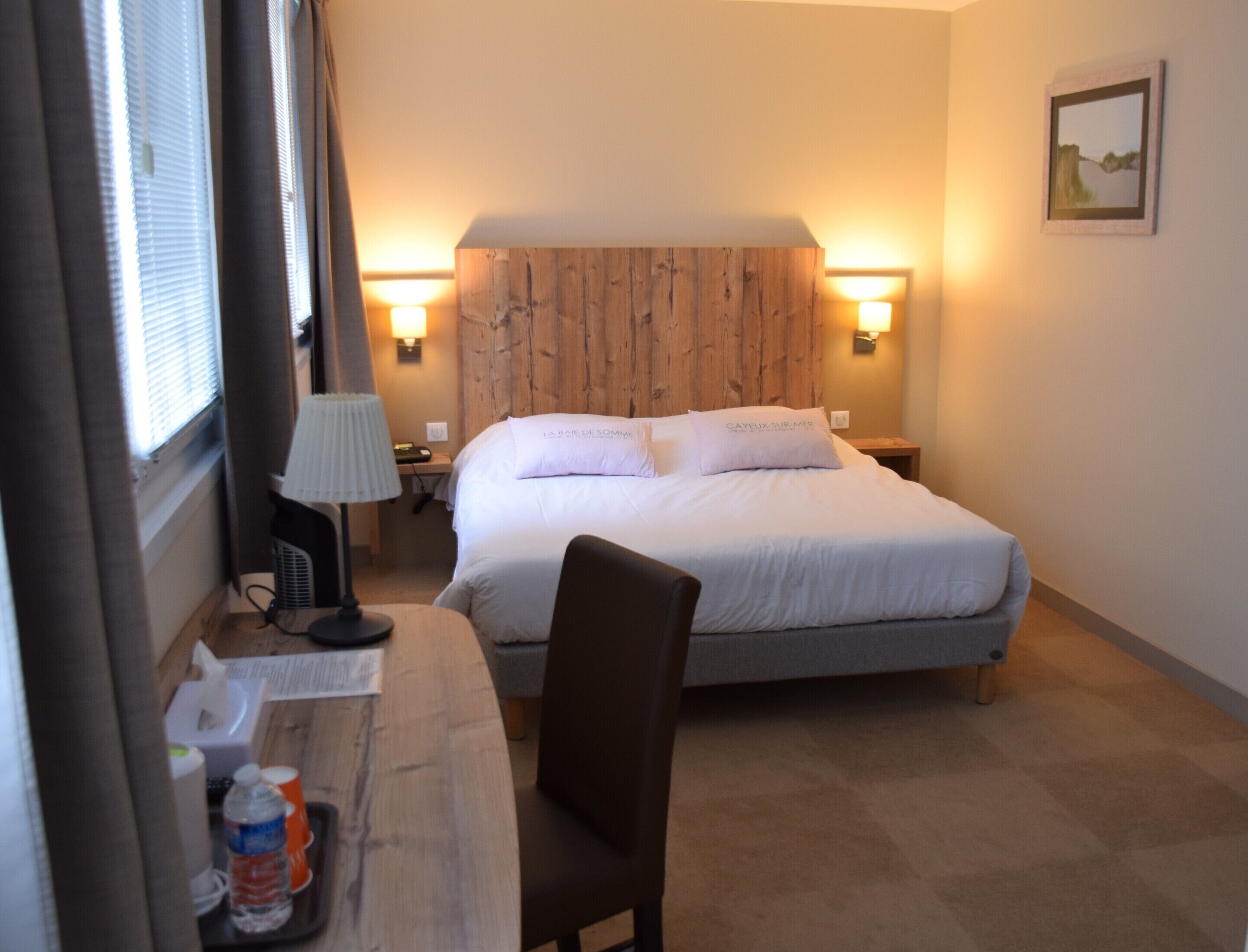 Een hotelkamer met een bed, nachtkastjes, een bureau, een stoel en een lamp.