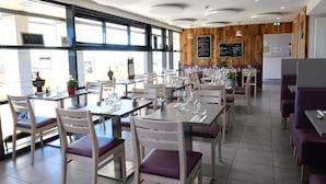 Un ristorante con diversi tavoli e sedie, una bacheca con i menu e vista sulla strada.