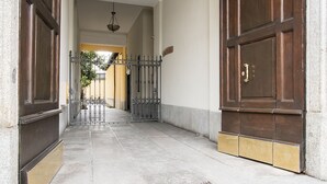 Um corredor com um portão de metal, uma porta de madeira e piso de azulejos.