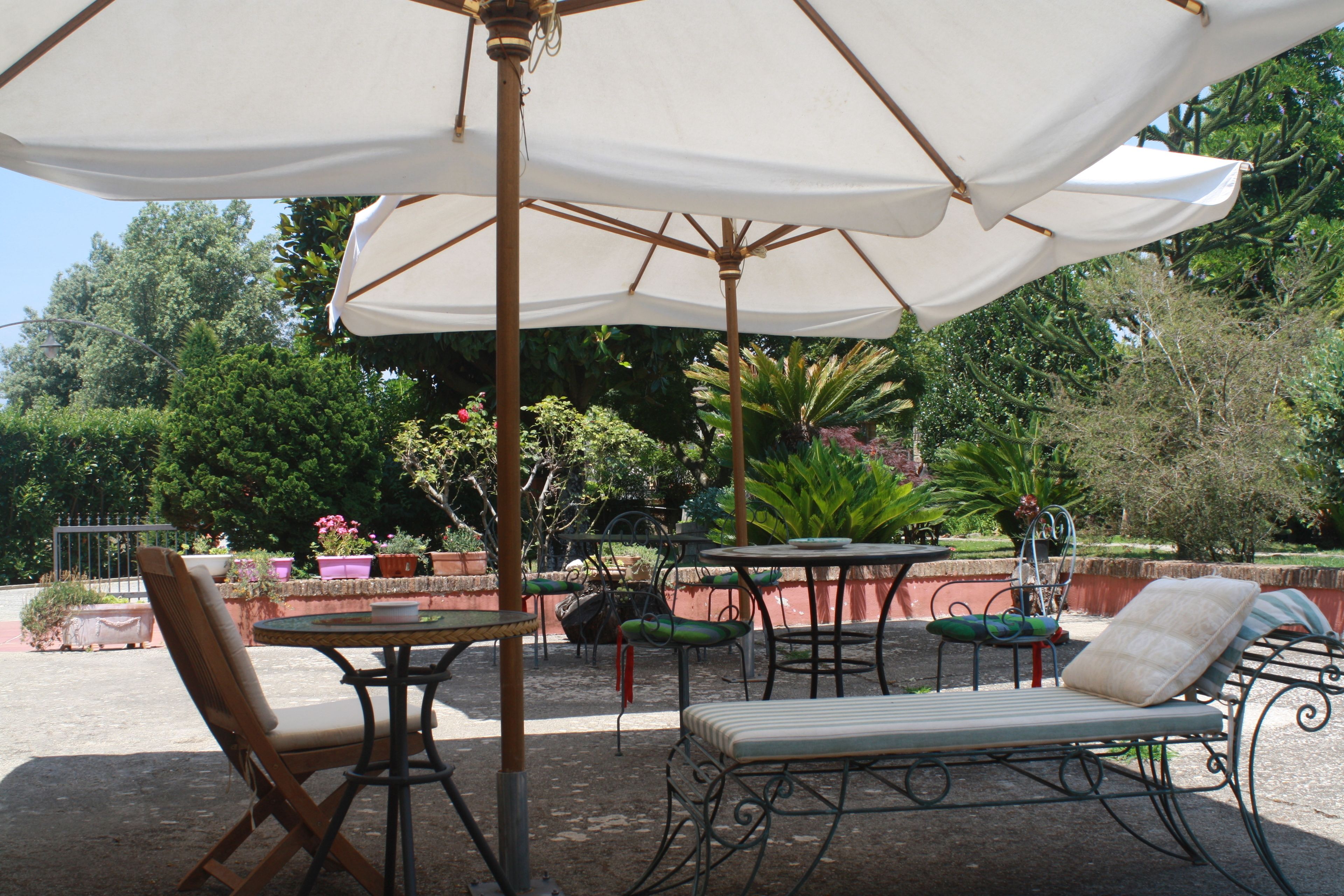 An outdoor patio with a table, chairs, and a lounge chair under a large umbrella.