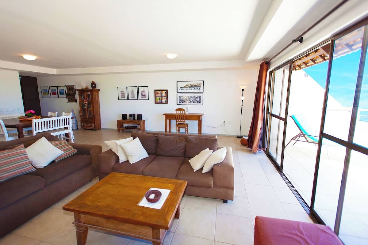 A living room with a brown sofa, a wooden coffee table, and a dining area with a table and chairs.