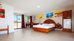 Una habitación de hotel con una cama grande, un escritorio, una silla, un armario y un refrigerador.