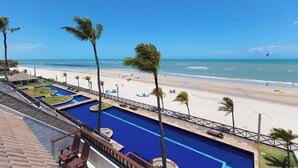 Un resort con piscina, playa y palmeras.