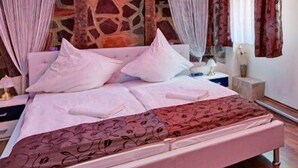 A bedroom with a bed, curtains, a stone wall, and a nightstand. - Hotel Restaurant Zum Ochsen (Bietigheim)