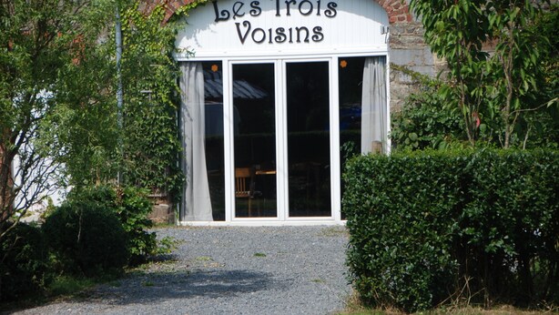 A building with a sign reading "Les Trois Voisins" and large windows. - B&B Les Trois Voisins (Gedinne)