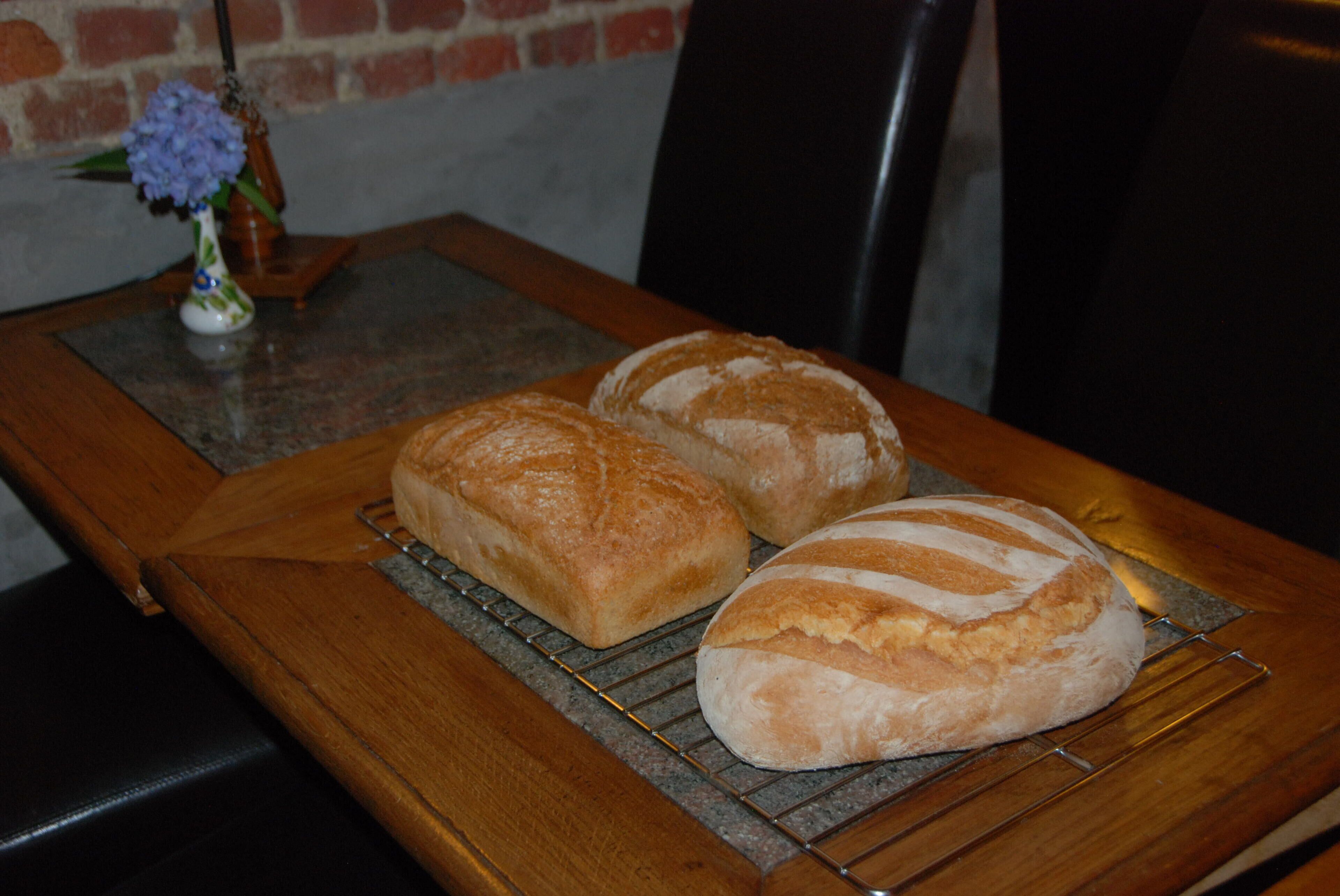 Two loaves of bread on a cooling rack on a wooden table.