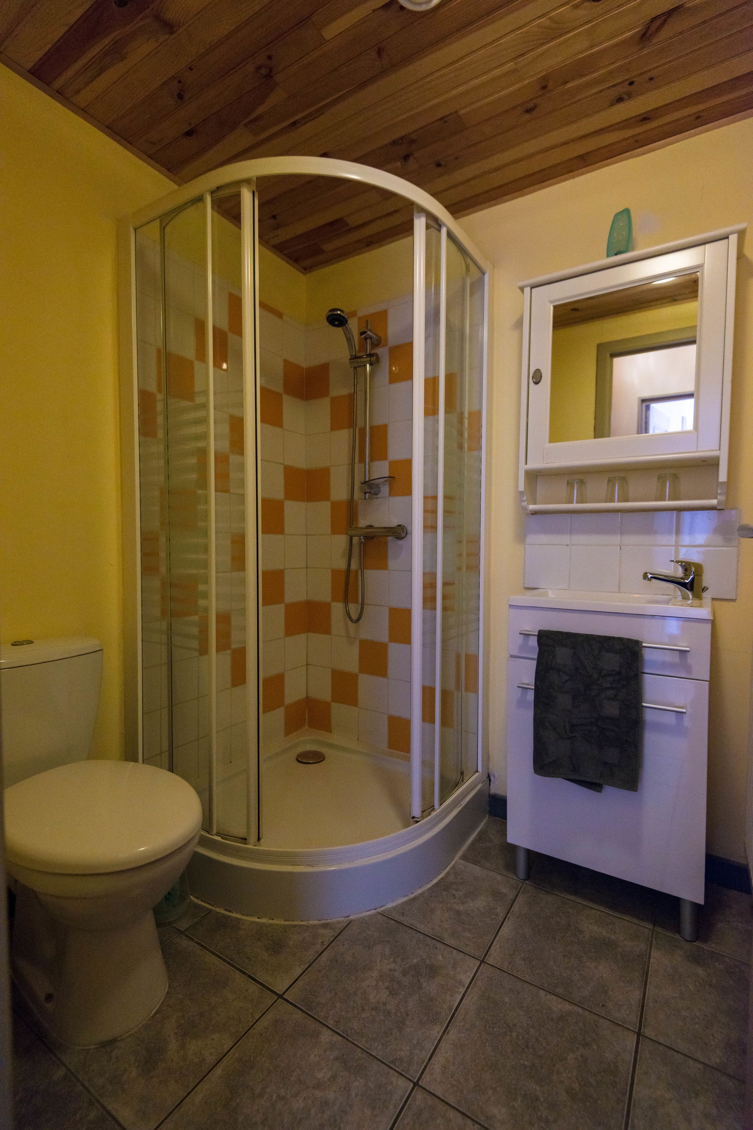 Un baño con ducha de vidrio, inodoro y lavamanos con una toalla colgada en la pared.