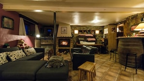 A cozy living room with a fireplace, a sofa, a coffee table, and a bar area. - B&B Les Trois Voisins (Gedinne)