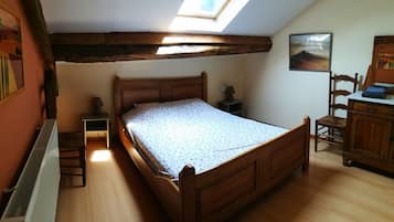 Une chambre à coucher avec un lit en bois, un puits de lumière, un radiateur et une petite table de chevet avec une lampe.