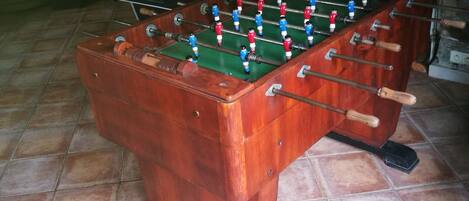 A wooden foosball table with a green playing surface and red, white, and blue player figures.