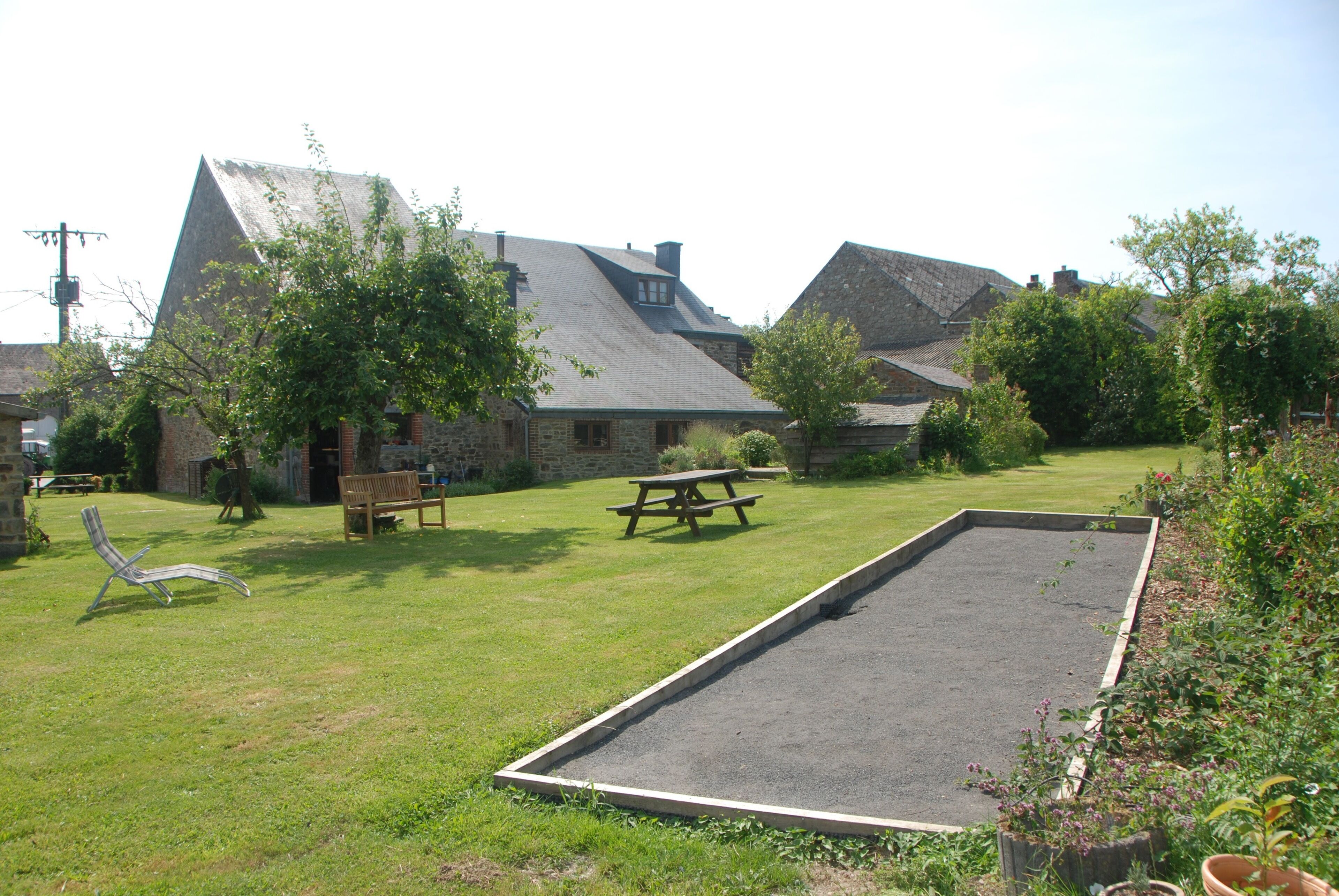 A courtyard with a picnic table, a lounge chair, and a rectangular play area.