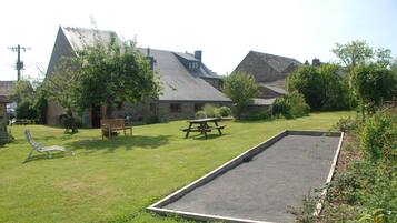 A courtyard with a picnic table, a lounge chair, and a rectangular play area.