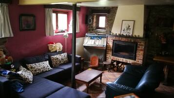 Una sala de estar con chimenea, un sofá, una mesita de centro y un televisor.