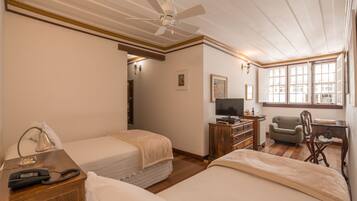 A hotel room with two beds, a desk with a television, a chair, and a wooden dresser.