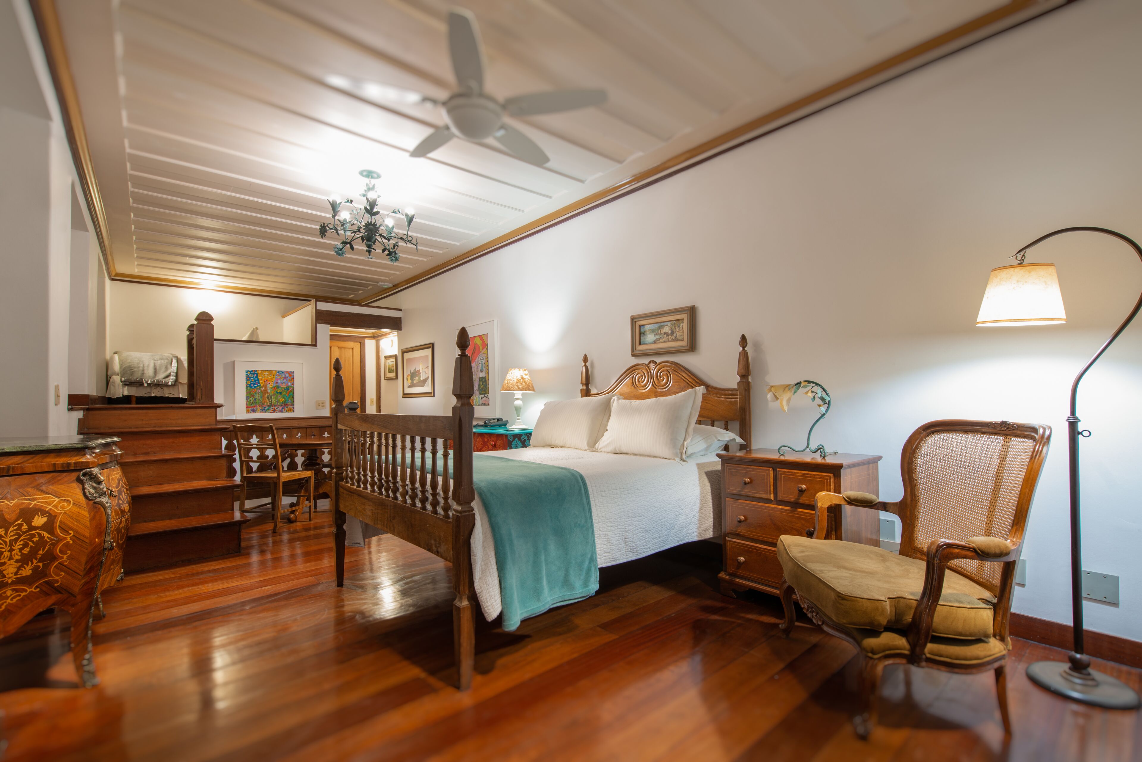 A bedroom with a wooden bed, a chair, a nightstand, and a desk.