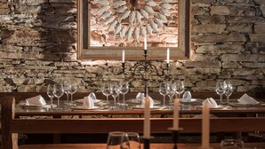 A restaurant with a stone wall backdrop, a framed fish artwork, and a table set for dining. - Pousada do Mondego (Ouro Preto)