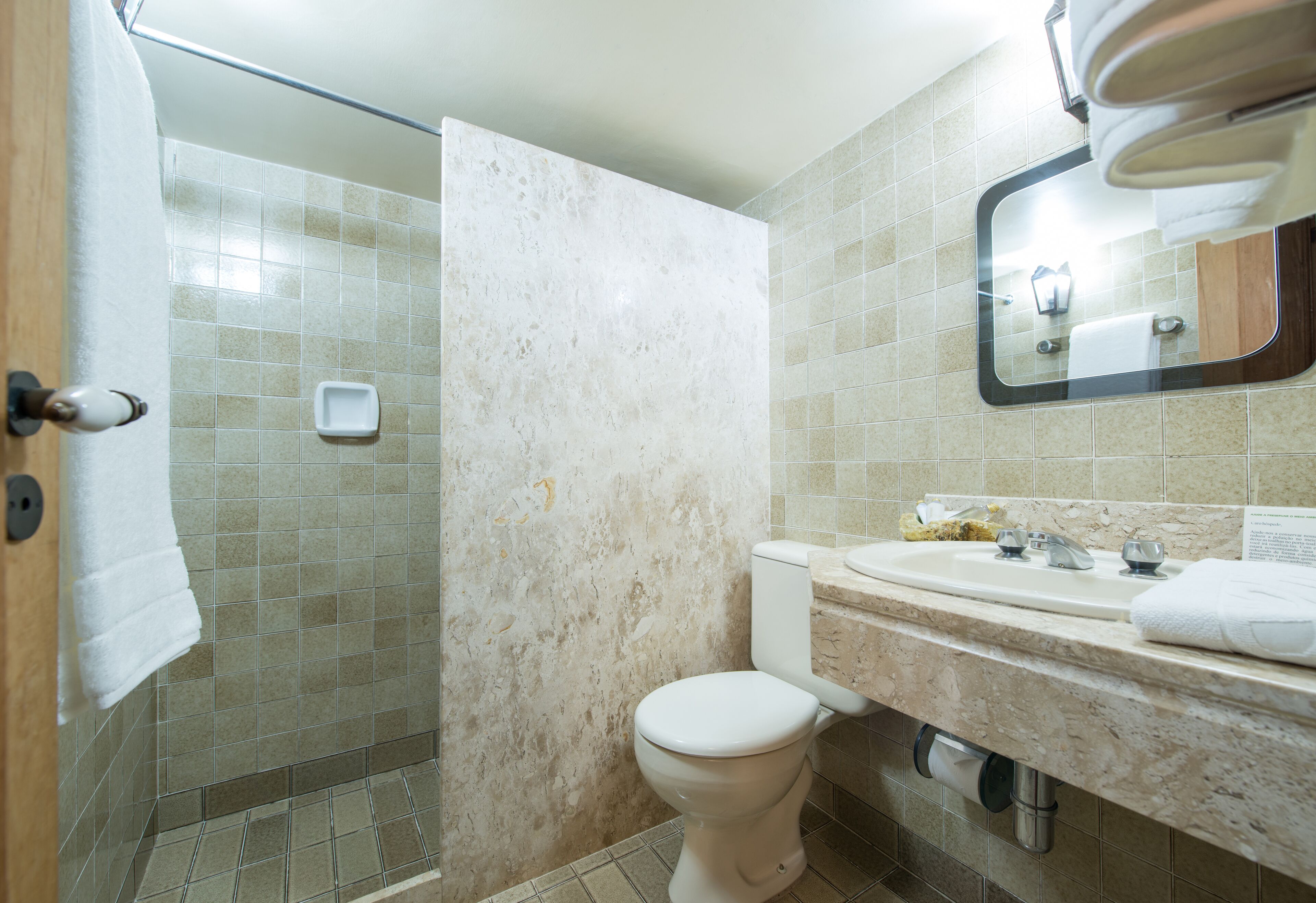 A bathroom with a shower, toilet, sink, and mirror.