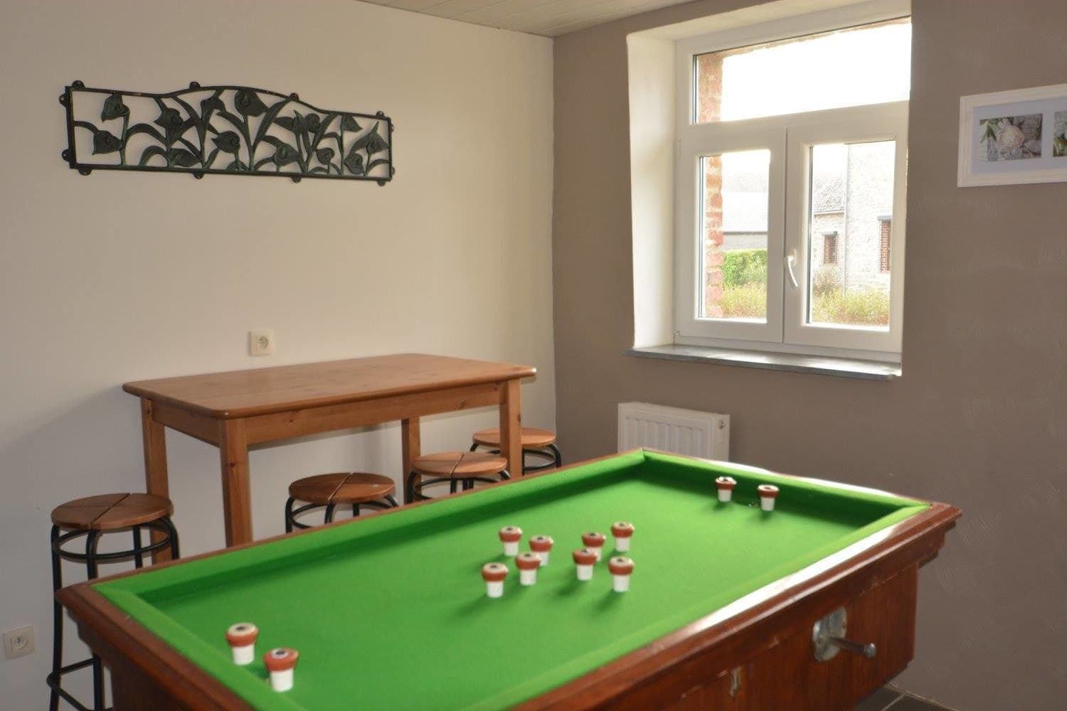 Een pooltafel met krukken, een houten tafel en een raam met uitzicht.