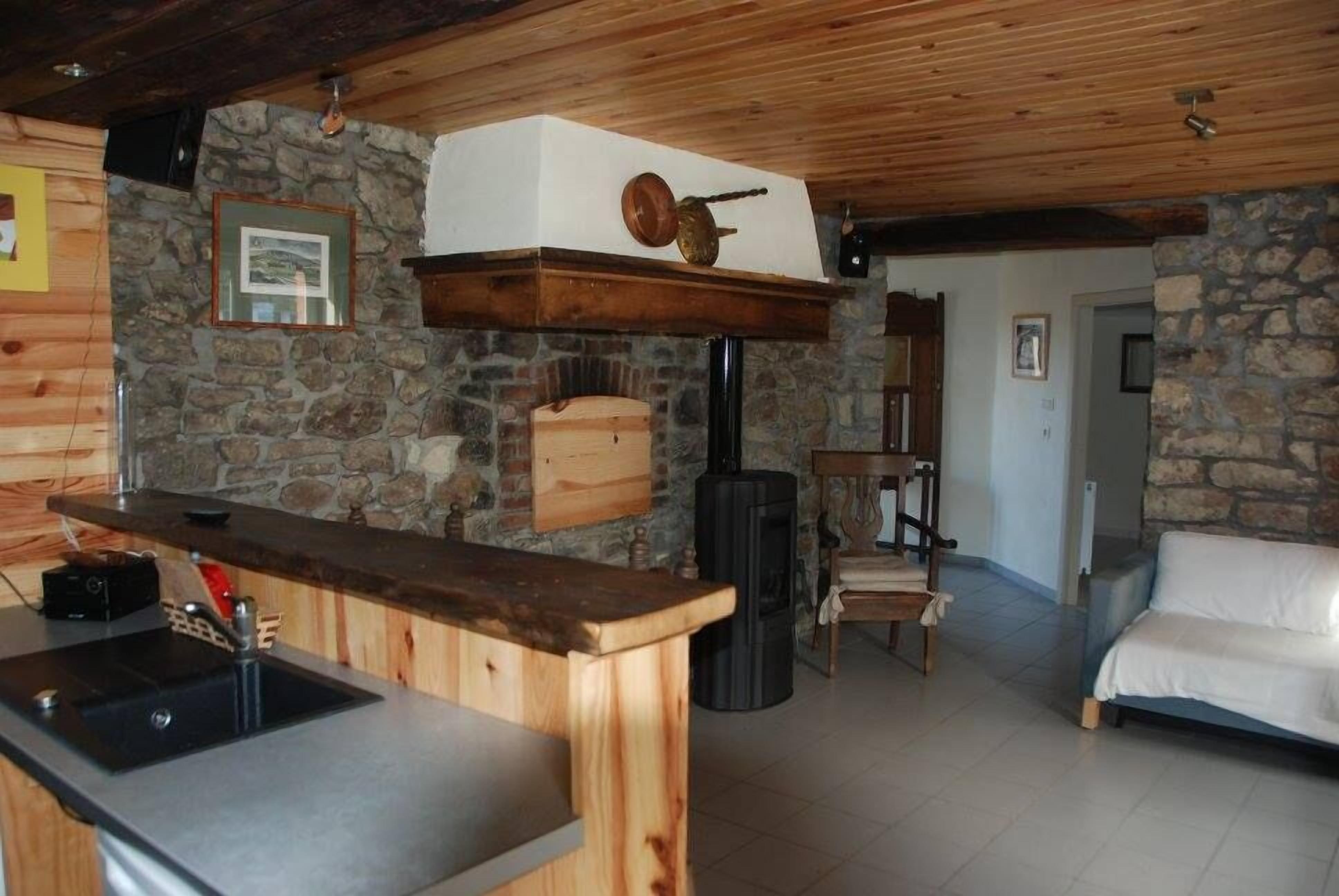 Eine rustikale Küche mit Steinwand, Holzplatte und eingebautem Ofen.