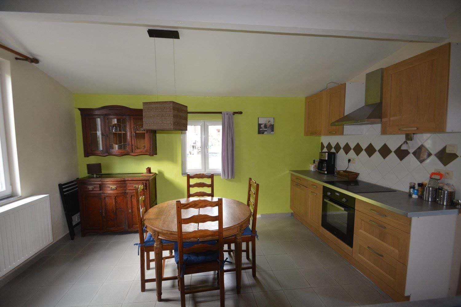Cocina compacta con armarios de madera, una mesa de comedor con sillas y una ventana que proporciona luz natural.