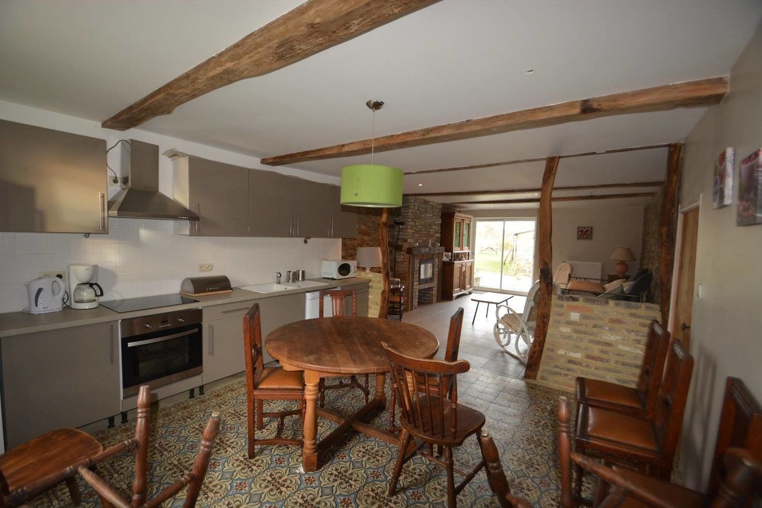 Una cocina con zona de comedor, vigas de madera, chimenea de piedra y vistas al exterior.