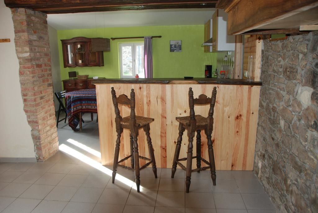Une cuisine avec des tabourets de bar en bois, une table à manger avec des chaises, et une vue sur l’espace repas.
