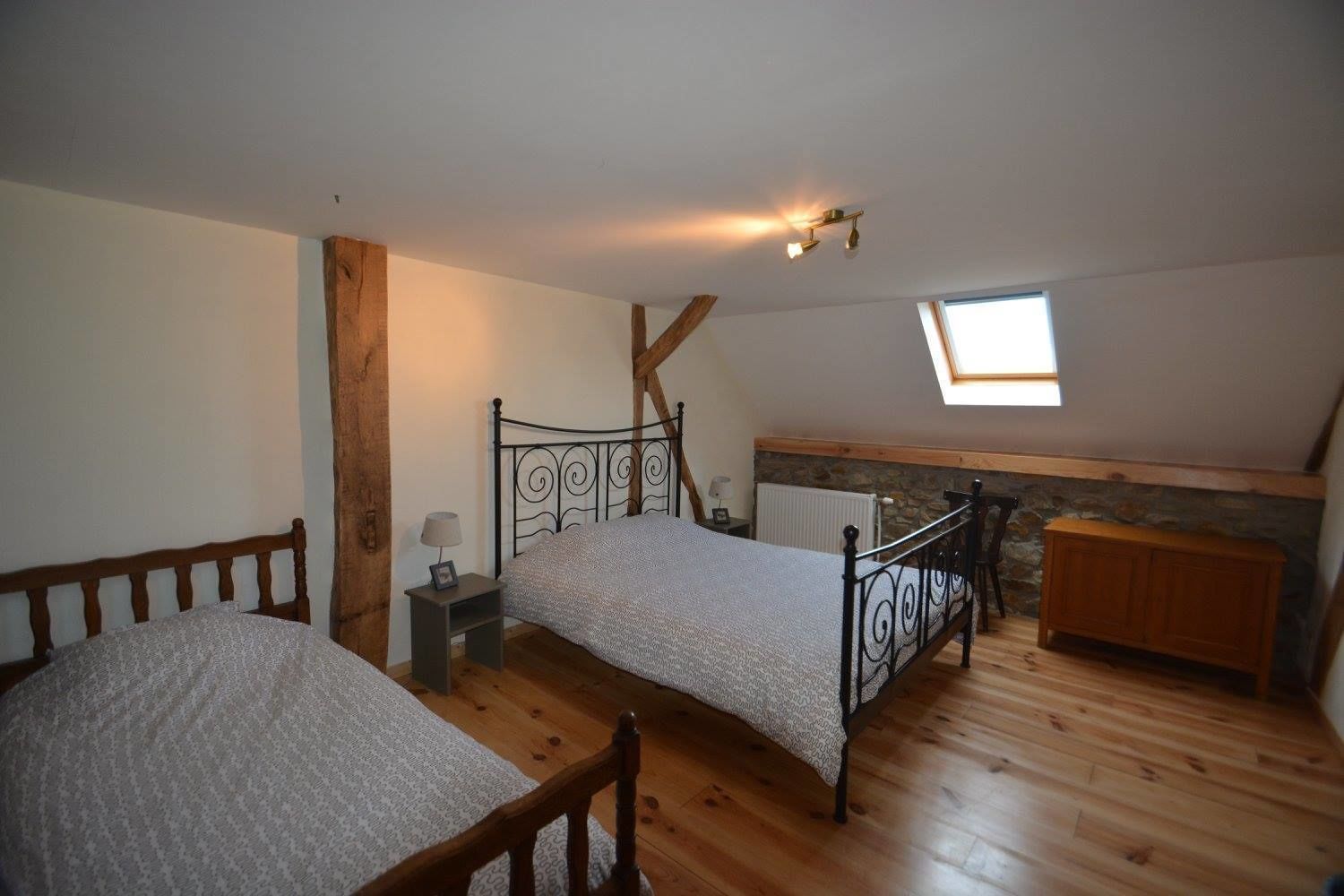 Ein Schlafzimmer mit zwei Betten, einem Holzschrank, einer Steinwand und einem Oberlicht.