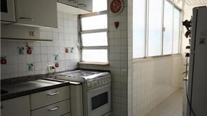 A kitchen with white cabinets, a sink, an oven, and a window. - GoHouse Visconde 802 (Rio de Janeiro)