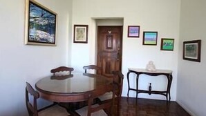 A dining area with a round wooden table and chairs, a small side table, and framed artwork on the walls. - GoHouse Visconde 802 (Rio de Janeiro)