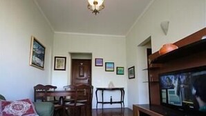 A living room with a television, a sofa, a dining table, and chairs. - GoHouse Visconde 802 (Rio de Janeiro)