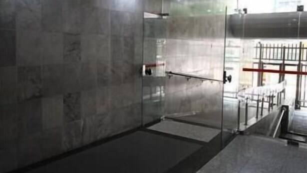 A modern, industrial-style room with a glass partition, metal railings, and a concrete floor. - GoHouse Visconde 802 (Rio de Janeiro)