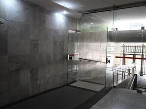 A modern, industrial-style room with a glass partition, metal railings, and a concrete floor. - GoHouse Visconde 802 (Rio de Janeiro)