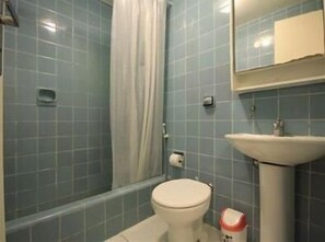 A bathroom with a toilet, sink, and shower area.