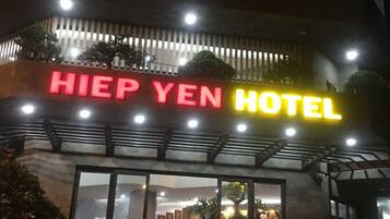 Esterno dell'Hotel Hiep Yen con insegna illuminata, ingresso in vetro e uno scooter parcheggiato davanti.